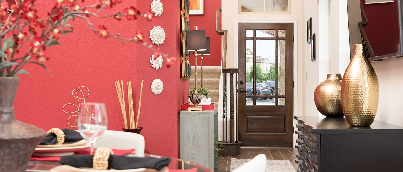 View from dining room of a vibrant salmon colored wall leading into an entryway and staircase.