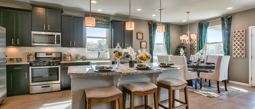 Near the dining area, a luxurious kitchen displays dark cabinetry, granite, and a large island with stools.