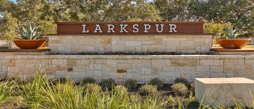 The Larkspur stone front entrance surrounded by Texas Hill Country landscaping.