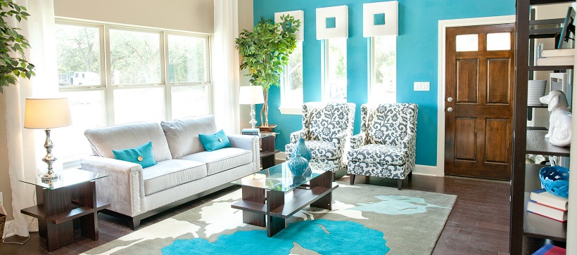 A vibrant living room with turquoise walls and white and turquoise furniture represents some of the best homes around Austin.