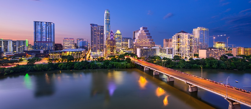 View of South Congress bridge leading into downtown Austin under an indigo sky.