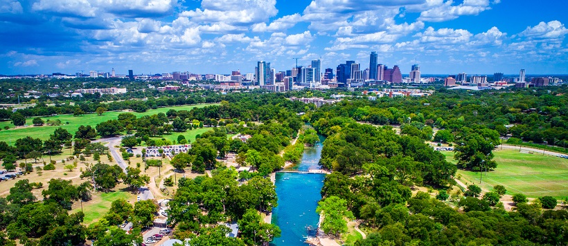 Skyline view of vibrant hill country and Lady Bird Lake leading towards downtown Austin, Texas.